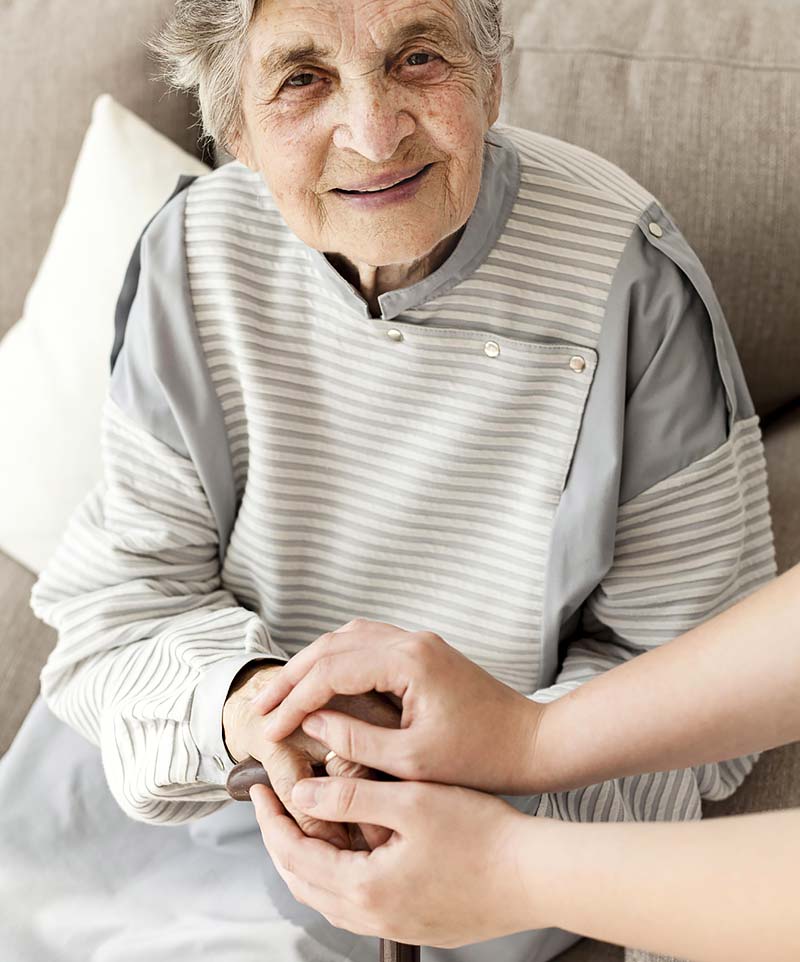 Mujer mayor sonriendo cogida de las manos.