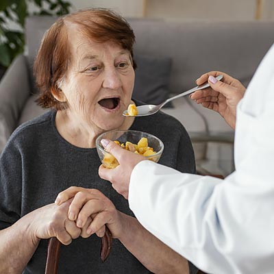 Enfermera alimentando a una mujer mayor.