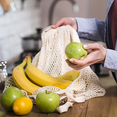 Bolsa encimera cocina con manzanas, plátanos y limones.